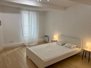 a white bedroom with a large bed and two tables at Le poète roucher in Montpellier