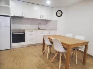 una cucina con un tavolo in legno e mobili bianchi di Charming Jasmin House a Viseu