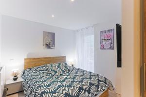 a bedroom with a bed with a black and white comforter at Mas Lac Blanc - Terrasse - Sauna - Parking in Orbey