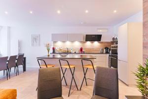 a kitchen with a counter and chairs in a room at Mas Lac Blanc - Terrasse - Sauna - Parking in Orbey