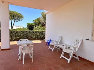 a patio with white chairs and tables and a wall at L'isola di Gianni by Ortigia Apartments in Plemmirio