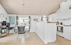 a kitchen with white cabinets and a table and chairs at Holiday Home Vejlby Klit in Harboør