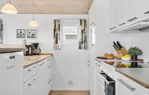 a white kitchen with white cabinets and a hallway at Holiday Home Vejlby Klit in Harboør +14 photos