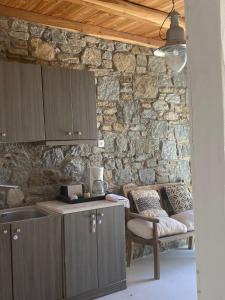 a kitchen with a stone wall and a table and a chair at Panormos Village,Mykonos in Mýkonos City