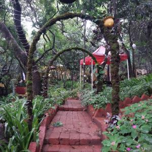 a brick path in a garden with a red tent at Gourish Resort in Mahabaleshwar