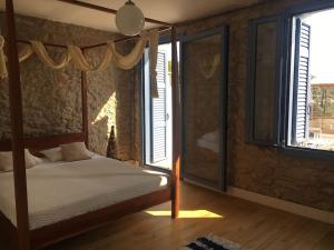 a bedroom with a canopy bed and windows at Lagada-Chios in Lagkáda
