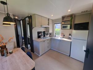 a kitchen with a table and a white refrigerator at Chalet Mullerthal in Reisdorf