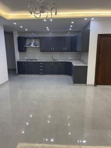 a large kitchen with blue cabinets and a tile floor at Magic View ماجيك فيو in Al Salt