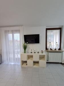 a white living room with a tv and a mirror at Casa Amelia lago Maggiore in Maccagno Inferiore