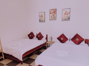 two beds in a room with red pillows on them at Hiệp Đạt Motel in Kon Tum