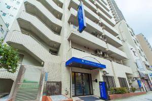un bâtiment avec un panneau bleu devant lui dans l'établissement HOTEL MYSTAYS Nippori, à Tokyo