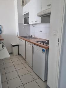 eine weiße Küche mit Spüle und Herd in der Unterkunft Appartement du golf terrasse piscine tout à pied in Ciboure + 4 Fotos