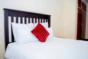 Ein rotes Kissen liegt auf einem Bett mit weißen Kissen. in der Unterkunft Freedom in Johannesburg