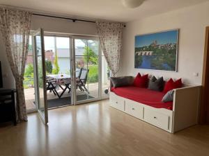 a bedroom with a bed with red pillows and a patio at Ferienwohnung Nauborn in Wetzlar mit großer Terrassse, ruhig gelegen in Wetzlar