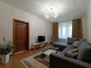 een woonkamer met een bank en een tv bij AURA on Tynystanova street 199 in Bisjkek