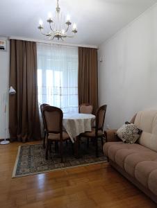 een eetkamer met een tafel, stoelen en een bank bij AURA on Tynystanova street 199 in Bisjkek +11 foto's