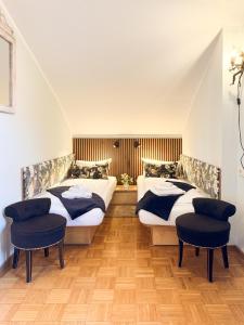 two beds in a room with two chairs at Villa Fantasia Budget Boutique Hotel in Füssen