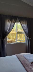 a bedroom with a window with a view of a deck at Winemaker's Rest- Two Bedroom House in Oudtshoorn