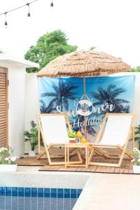 ein Paar Stühle und ein Sonnenschirm neben einem Swimmingpool in der Unterkunft Teddy House Cozy 3BD Poolvilla near Jomtien beach in Ban Huai Yai