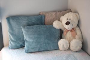 a teddy bear sitting on a bed next to a pillow at Otulina Błonie in Klukowo +27 photos