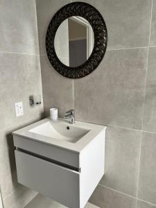 a bathroom with a white sink and a mirror at Sweet Daisies Apartment in Mbabane