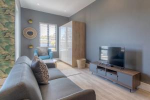 a living room with a couch and a flat screen tv at Trebuchet Studio Apartment in Somerset West +4 photos