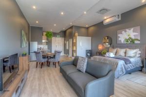 a bedroom and living room with a bed and a couch at Trebuchet Studio Apartment in Somerset West