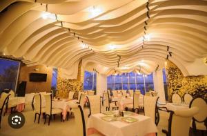 a restaurant with white tables and chairs and a large ceiling at White Tower Mamaia Apartament 608 in Mamaia