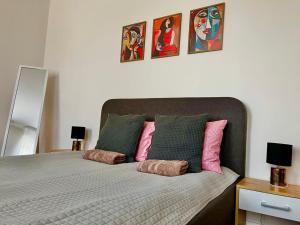 1 dormitorio con 1 cama con almohadas rosas y verdes en Tikrai nelis, en Liepāja