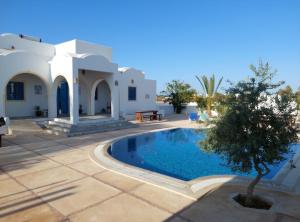 a villa with a swimming pool in a yard at Résidence Ulysse Djerba in Mezraya