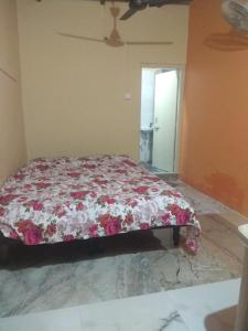 a bedroom with a bed with a floral comforter at Ashok Home Stay in Hampi