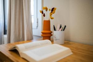 a book sitting on a table with a vase of flowers at Sui Tetti di Bologna centro, Casa Dei Colori in Bologna +66 photos