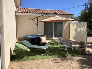 a patio with an umbrella and chairs and a pool at Au Petit Bueix in Sillans-la Cascade