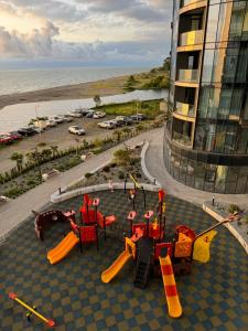 a playground with play equipment in front of a building at Tropical garden apartments in Batumi