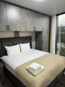 a bedroom with a bed with white sheets and a window at Tropical garden apartments in Batumi