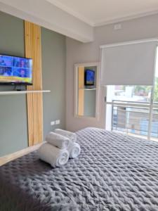 a room with a bed with towels and a television at Departamentos Güemes in San Fernando del Valle de Catamarca