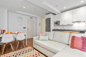 a living room with a white couch and a kitchen at Plaza del Carmen in Gijón