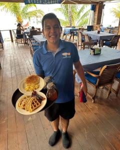 a man holding a tray of food on a table at Blue Bahia Resort in Sandy Bay