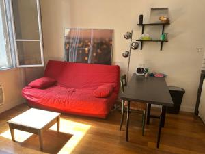 a living room with a red couch and a table at Studio de charme 20m2 à Saint-Mandé in Saint-Mandé +2 photos