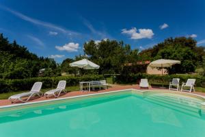 a swimming pool with chairs and tables and umbrellas at Agriturismo Il Sughereto - Appartamento Cattleya in Podere Caminino