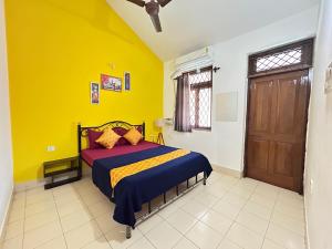 a bedroom with a bed with a yellow wall at Muffy’s Vacation Apartment in Baga