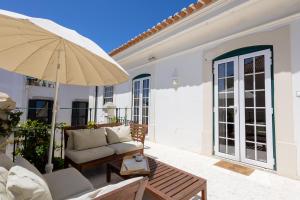 eine Terrasse mit einer Couch und einem Sonnenschirm in der Unterkunft Charming Beach House - by Smarthomes in São Martinho do Porto