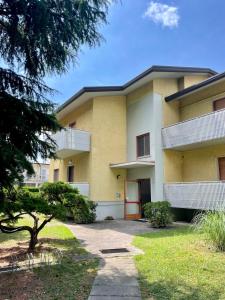 a large yellow building with a tree in front of it at Casa Lucia in Lignano Sabbiadoro