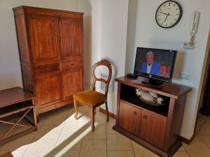 a room with a tv and a chair and a clock at Appartamento con posto auto in Viareggio