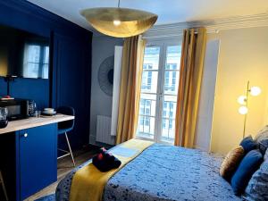 a blue bedroom with a bed and a desk and a window at Le Royal - Vieux Rennes in Rennes