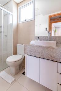 a white bathroom with a toilet and a sink at PALMAS EXPERIENCE - APARTAMENTO CONTEMPORÂNEO, vista serra, na quadra do shopping in Palmas