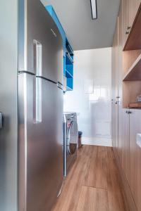 a stainless steel refrigerator in a kitchen with wooden floors at PALMAS EXPERIENCE - APARTAMENTO CONTEMPORÂNEO, vista serra, na quadra do shopping in Palmas