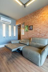 a living room with a couch and a brick wall at PALMAS EXPERIENCE - APARTAMENTO CONTEMPORÂNEO, vista serra, na quadra do shopping in Palmas