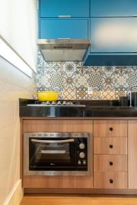 a kitchen with a black microwave and blue cabinets at PALMAS EXPERIENCE - APARTAMENTO CONTEMPORÂNEO, vista serra, na quadra do shopping in Palmas