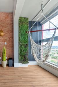 a hammock hanging in a room with a green wall at PALMAS EXPERIENCE - APARTAMENTO CONTEMPORÂNEO, vista serra, na quadra do shopping in Palmas